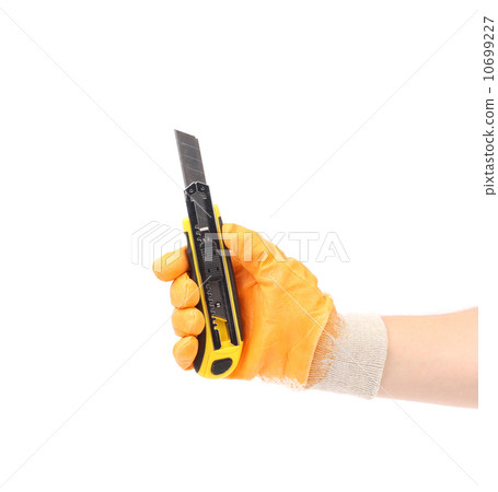 Hand holds yellow stationery knife. Hand holds yellow stationery knife. 10699227