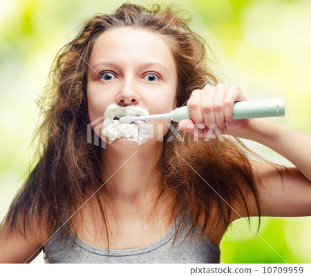 Shaggy young woman using electric toothbrush 10709959
