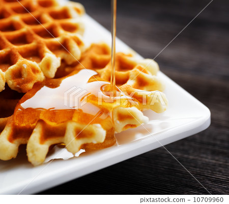 Honey pouring on a fresh waffles 10709960