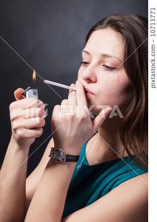 Beautiful young woman is smoking cigarette on black background Beautiful young woman is smoking cigarette on black background 10713771