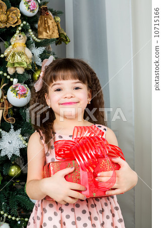 Happy little girl with christmas present smiling 10715166