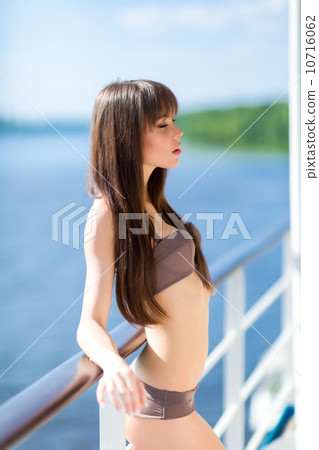 Sexy woman in stylish swimsuit standing on the aft of a sailing Sexy woman in stylish swimsuit standing on the aft of a sailing 10716062