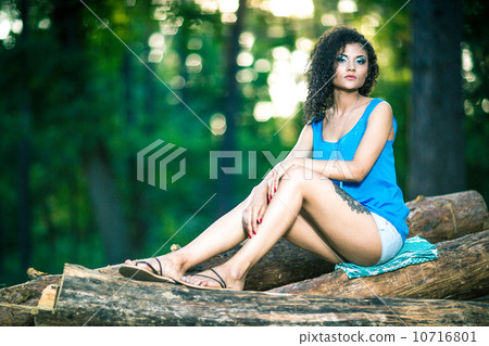 Beautiful Young Woman sitting on log posing Beautiful Young Woman sitting on log posing 10716801
