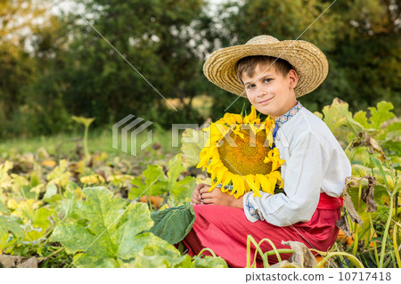 Young happy boy hold sunflower in a garden Young happy boy hold sunflower in a garden 10717418