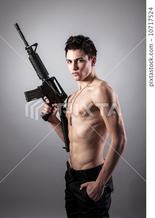 Handsome bare-chested soldier is holding a rifle 10717524