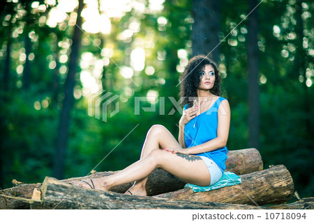 Beautiful Young Woman sitting on log posing 10718094
