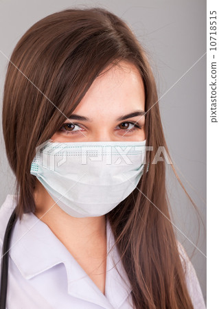 Doctor / nurse smiling behind surgeon mask. Closeup portrait of 10718515