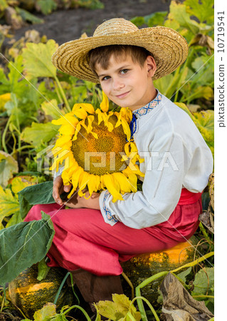 Young happy boy hold sunflower in a garden Young happy boy hold sunflower in a garden 10719541