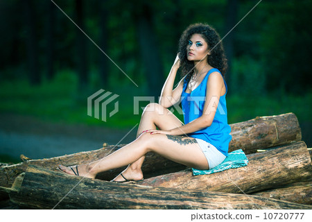 Beautiful Young Woman sitting on log posing 10720777