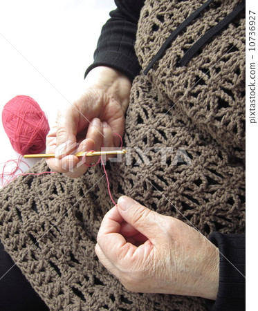 A woman holding a crocheted hand-knitted clothes (senior) 10736927