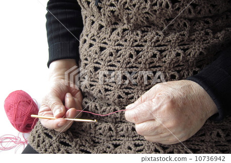 A woman holding a crocheted hand-knitted clothes (senior) 10736942