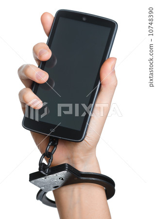 Mobile phone addiction concept. Smartphone and handcuff in hand Mobile phone addiction concept. Smartphone and handcuff in hand 10748390