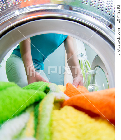 householder woman loading clothing into washing machine householder woman loading clothing into washing machine 10748393