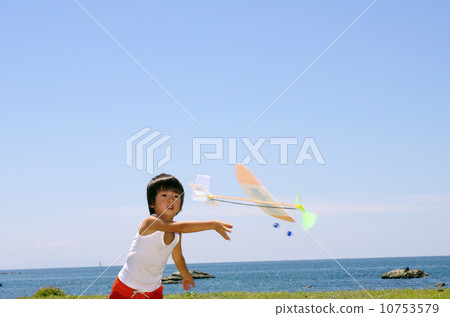 Children flying a model plane on the coast 10753579
