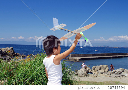 Children flying a model plane on the coast 10753594