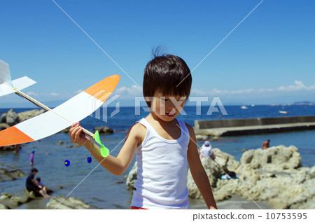 A child walking on the beach with a model plane 10753595