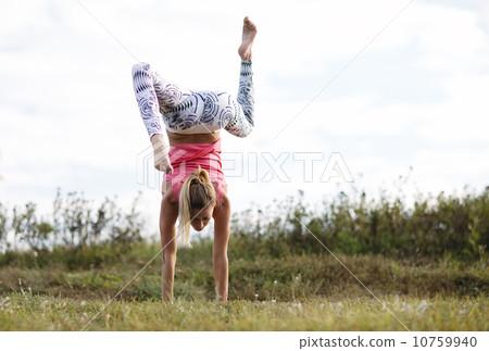 Agile young woman doing a handstand Agile young woman doing a handstand 10759940