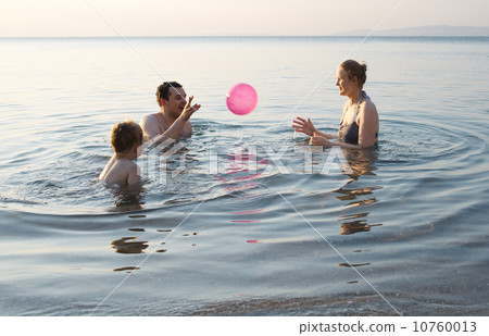 Young family playing with ball at sunset 10760013