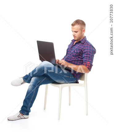Young man sitting in chair and working on lapto Young man sitting in chair and working on lapto 10773830