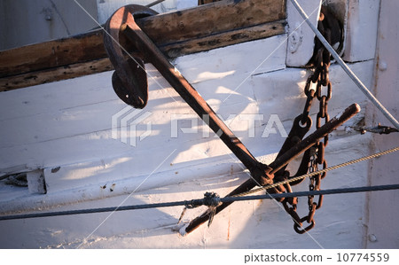 Close up photo of an old ship's mooring anchor on white painted hull 10774559