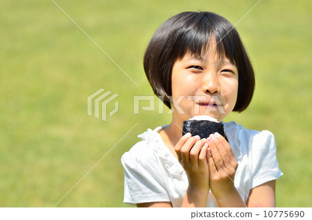 A girl who eats onigiri at the lawn plaza 10775690