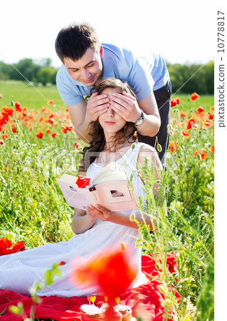 Young happy couple on a meadow full of poppies Young happy couple on a meadow full of poppies 10778817