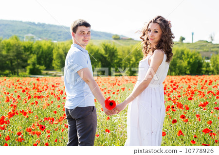 Young happy couple on a meadow full of poppies 10778926