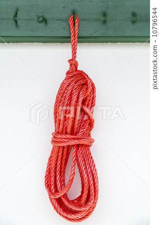 red rope hanging on a green hook on a white wall 10796544