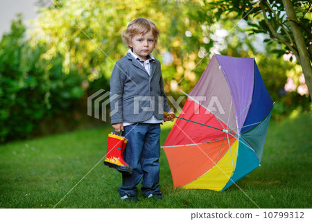 Little cute toddler boy with colorful umbrella and boots, outdoo Little cute toddler boy with colorful umbrella and boots, outdoo 10799312