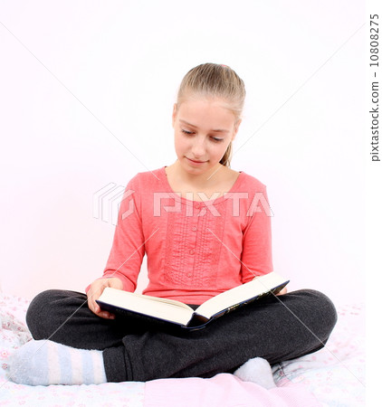 Blond girl reads interesting book sitting on bed 10808275