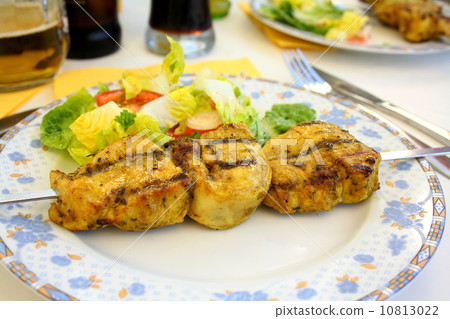 Grilled chicken fillet on metal skewer with salad 10813022