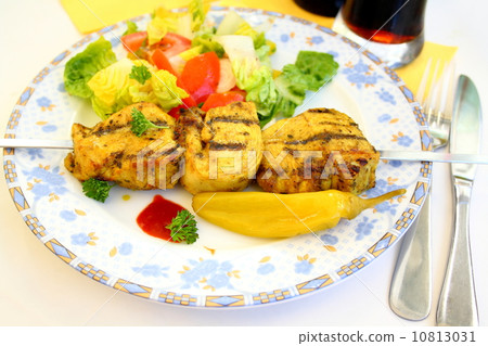 Grilled chicken fillet on metal skewer with salad, soft focus 10813031