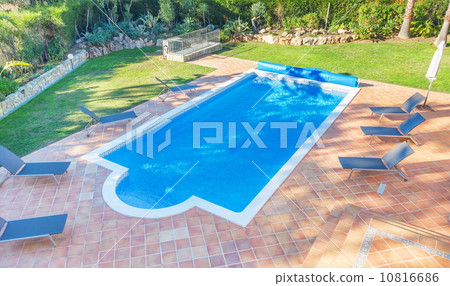 Summer pool in the courtyard near the house. Sunbeds for relaxin 10816686