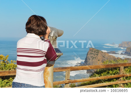 Girl tourist watching a beautiful sea landscape from the telescope. 10816695