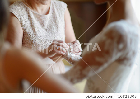 Helping a bride to put her wedding dress on 10823303