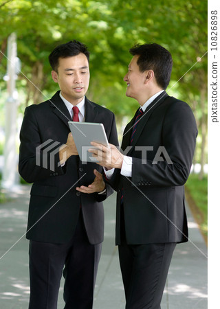 Two successful entrepreneur business men standing along promenade using mobile device tablet iPad Two successful entrepreneur business men standing along promenade using mobile device tablet iPad 10826898