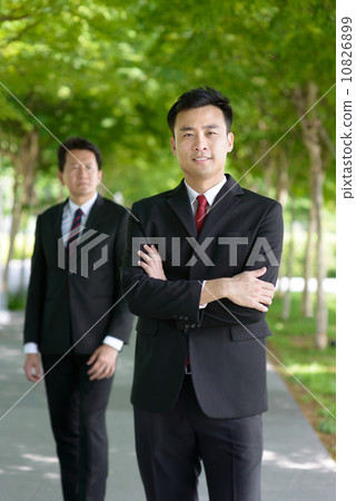 Two successful entrepreneur business men standing front and back along promenade 10826899