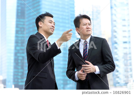 Two successful entrepreneur business men standing in front of glass building  10826901