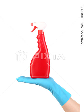 Hand in glove holding red plastic spray bottle 10849956