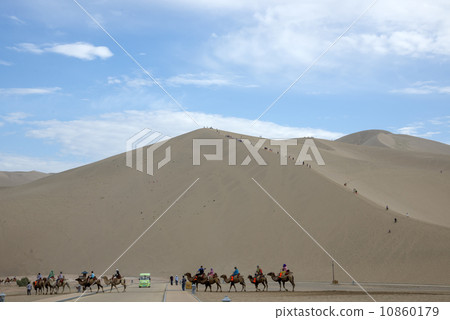 DUNHUANG, CHINA-August 22: camels walking in the Mingsha sand dunes mountain on August 22, 2013 in Dunhuang, China. DUNHUANG, CHINA-August 22: camels walking in the Mingsha sand dunes mountain on August 22, 2013 in Dunhuang, China. 10860179