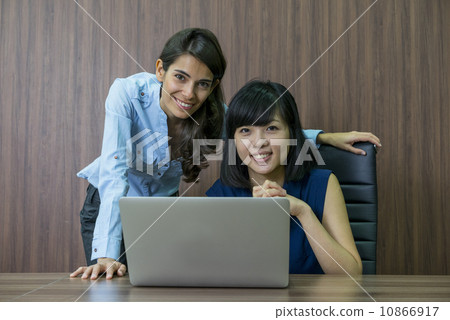 Two Female Asian executives having a discussion at the desk, looking into the laptop 10866917