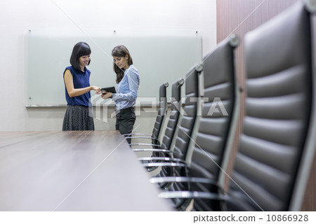 Two Female Asian executives having a discussion using a tablet in the conference room. Two Female Asian executives having a discussion using a tablet in the conference room. 10866928