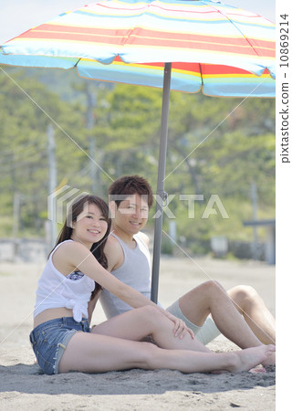 擁抱在沙灘傘下的年輕夫婦 擁抱在沙灘傘下的年輕夫婦 10869214