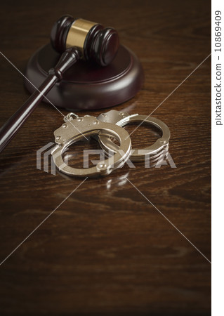 Gavel and Pair of Handcuffs on Table 10869409