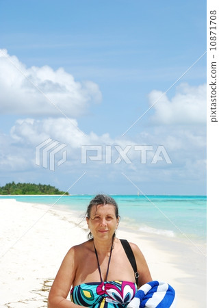 Beautiful senior woman walking on a tropical beach Beautiful senior woman walking on a tropical beach 10871708