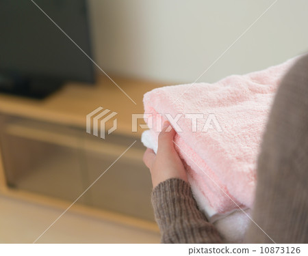 A woman's back as she folds a bath towel. 10873126