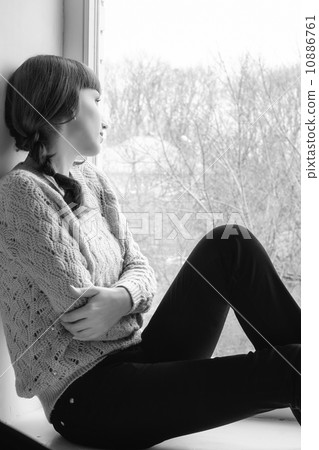Young woman looking through window 10886761