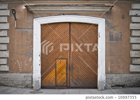 Stone wall of an old building with old weathered wooden gate with peephole 10897355