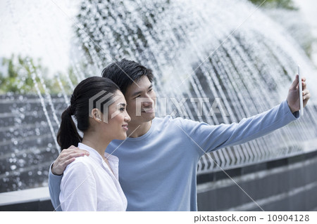 Asian couple using tablet to take a selfie. Asian couple using tablet to take a selfie. 10904128