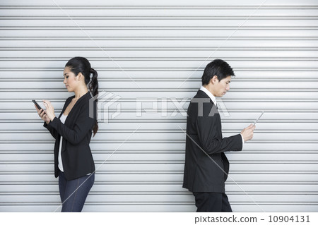 Two Chinese business colleagues using tech device's Two Chinese business colleagues using tech device's 10904131